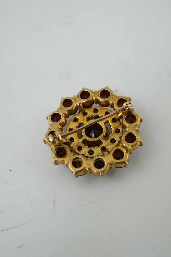 A 1970's 9ct gold and garnet cluster set circular brooch, 27mm. Condition - fair